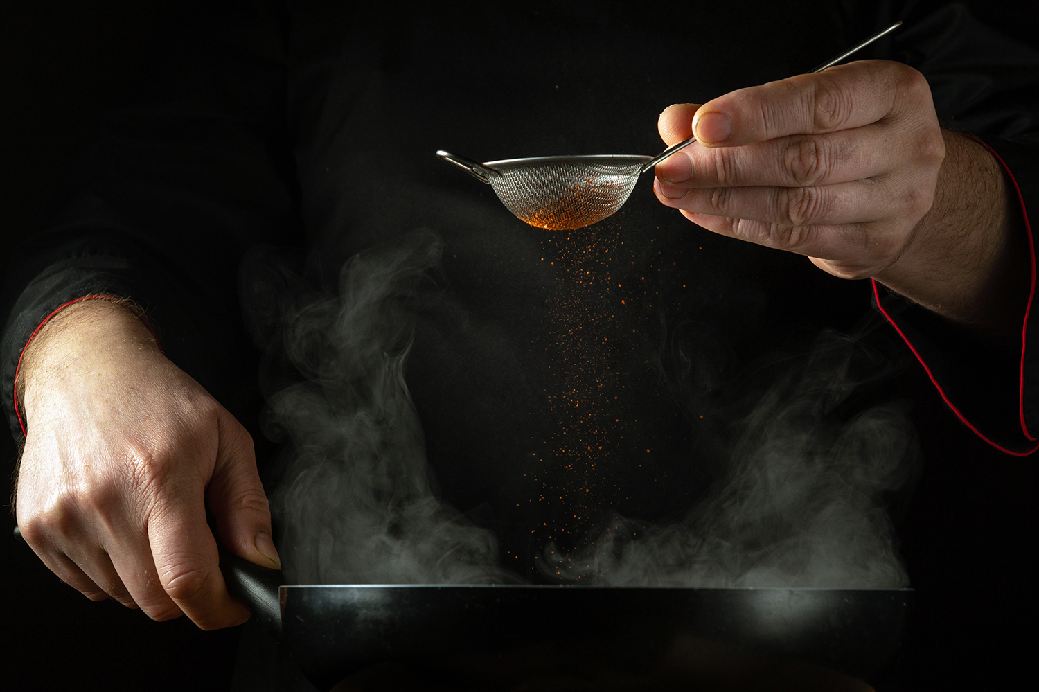 The,Chef,Adds,Aromatic,Paprika,To,A,Hot,Frying,Pan The chef adds aromatic paprika to a hot frying pan by hand. Low key concept of preparing a delicious lunch in the kitchen of a public house. Grande cuisine.
